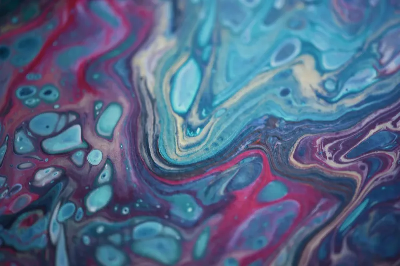 Remolino abstracto de tinta turquesa, púrpura y roja en primer plano