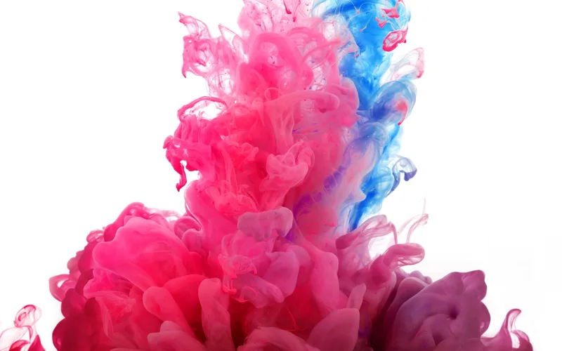 Nube de tinta rosa y azul disolviéndose en agua sobre fondo blanco