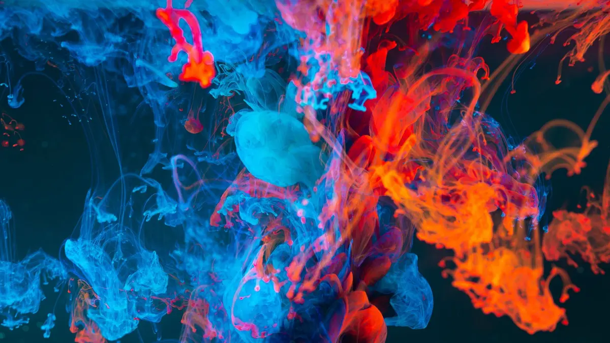 Imagen abstracta de humo de tinta azul y roja entrelazándose sobre fondo oscuro