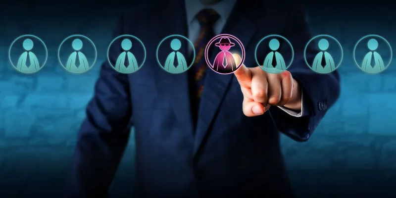 Hombre de traje señalando el icono rosa de un intruso entre empleados
