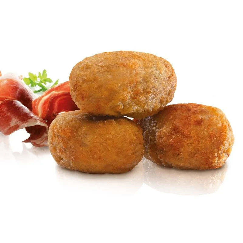 Tres croquetas fritas apiladas junto a lonchas de jamón ibérico